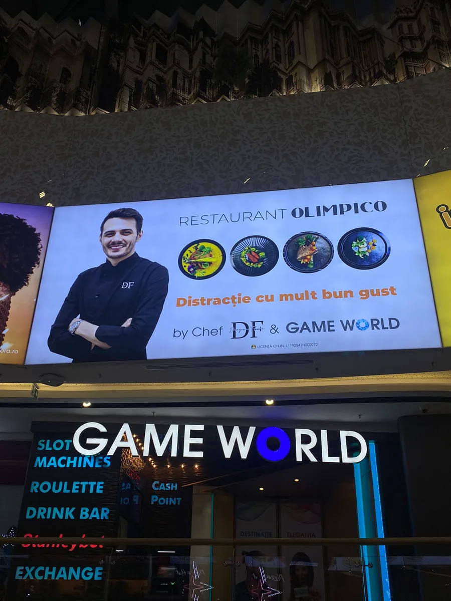 Casetă luminoasă Restaurant Olimpico și casetă Game World pe fațada unui complex