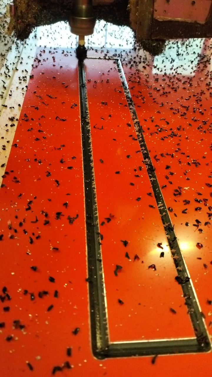 Freza CNC taie conturul unei piese într-o placă de plexiglas portocaliu translucid — Lartek Grup